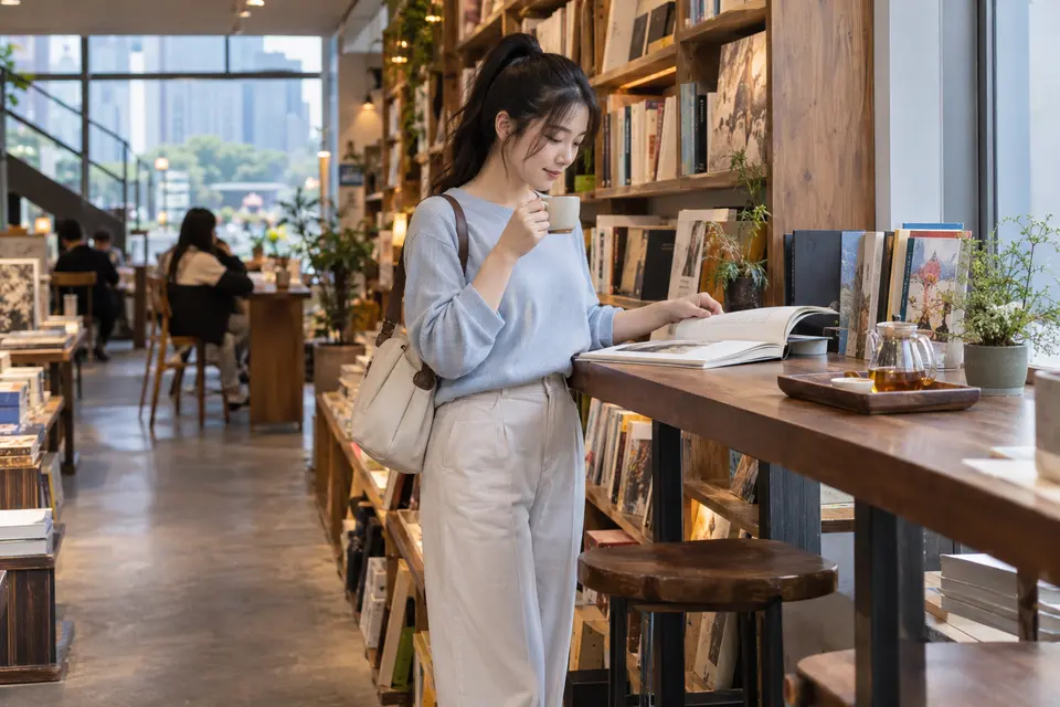 独立书店内，一位年轻女性边阅读边饮茶的场景